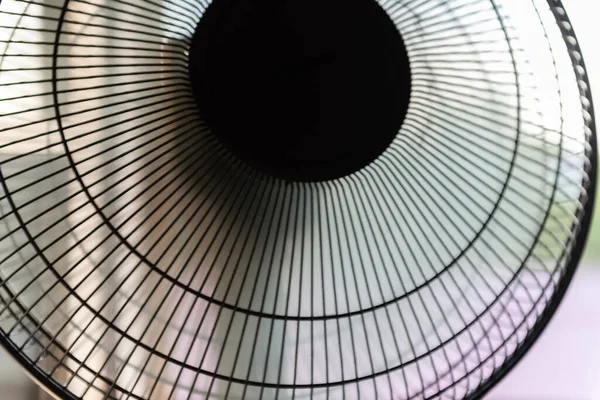 Fan turbine in front of a window. The electric fan slows down and resumes movement.