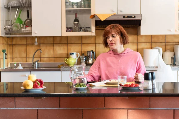 Genç ve güzel bir kadın mutfağında tek başına yemek yiyor..