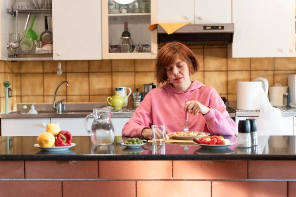 Genç ve güzel bir kadın mutfağında tek başına yemek yiyor..