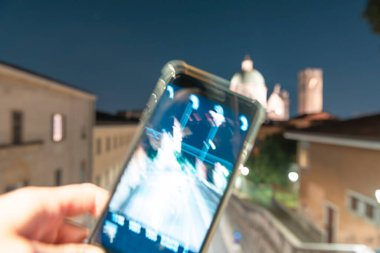 Duomo Nuovo Kubbesi 'nin akıllı telefonuyla gece görüşü şehrin hareketi, Roma Katolik kilisesi ve Brescia, Lombardiya' nın tarihi merkezi, İtalya 'nın kuzeyindeki Palazzo del Broletto Kulesi.