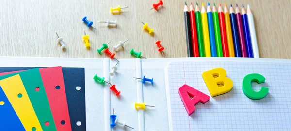 Kleurrijke samenstelling van schoolspullen en brieven op de withe houten achtergrond. Een spandoek. Plat gelegd. Terug naar schoolconcept. — Stockfoto