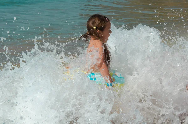 Joyeux éclaboussures d'enfants sur l'océan. Le gamin sourit et se baigne dans la mer. Belle côte de l'océan, un enfant se joue sur le bord de la mer. Fille à la mer. — Photo