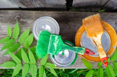 Boya fırçaları ve ahşap bir bankta üzerinde mavi ve kahverengi boya bulunan teneke kutular fotokopi alanı olan düz bir zemin üzerinde yatıyordu. ÇEVİR