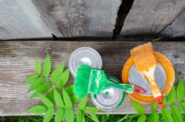 Boya fırçaları ve ahşap bir bankta üzerinde mavi ve kahverengi boya bulunan teneke kutular fotokopi alanı olan düz bir zemin üzerinde yatıyordu. ÇEVİR