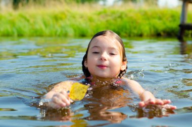 Sudaki genç ve güzel kıza yaklaş. Nehirde yüzen portre çocuğu. Tatil ve yaz konsepti.
