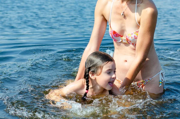 Шестилетняя девочка купалась с матерью в озере ясным летним днем. Концепция праздника. — стоковое фото