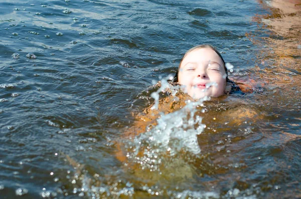 Νεαρό εξάχρονο κορίτσι κολυμπά σε μια λίμνη μια καθαρή καλοκαιρινή μέρα. Έννοια διακοπών. — Φωτογραφία Αρχείου