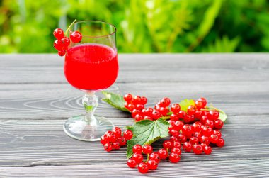 Taze kırmızı üzümlü içecek ve yeşil bahçedeki ahşap masada sulu böğürtlen..