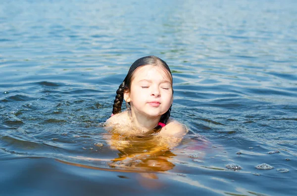 Крупный план молодой красивой девушки в воде. Портрет ребенка, плавающего в реке. Отпуск и летняя концепция. — стоковое фото