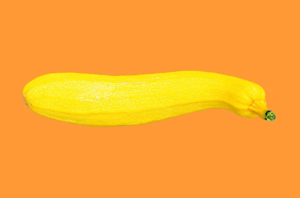 Gul zucchini på orange bakgrund. Nytt koncept för grödor. Isolera, ovanifrån. — Stockfoto