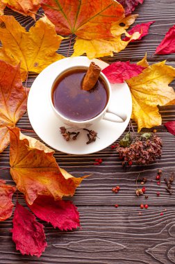 Baharatlı kahve, tarçın, karanfil ve kırmızı biber. Ahşap arka planda düşen sonbahar akçaağaç yaprakları.