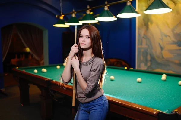 Girl with a cue in her hands playing billiards — Stock Photo, Image