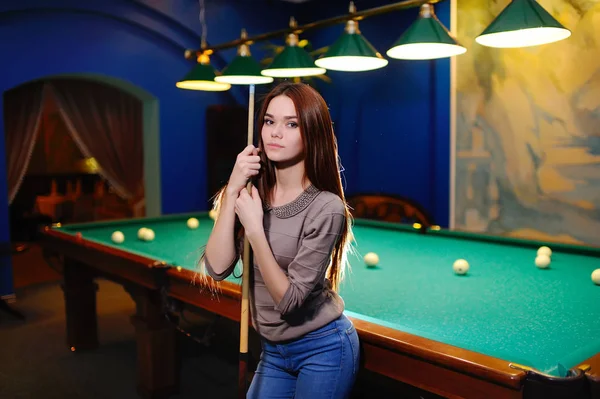 Girl with a cue in her hands playing billiards — Stock Photo, Image