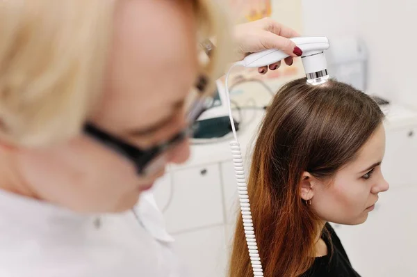 Dermatólogo examina el cabello de una mujer paciente usando un dispositivo especial — Foto de Stock