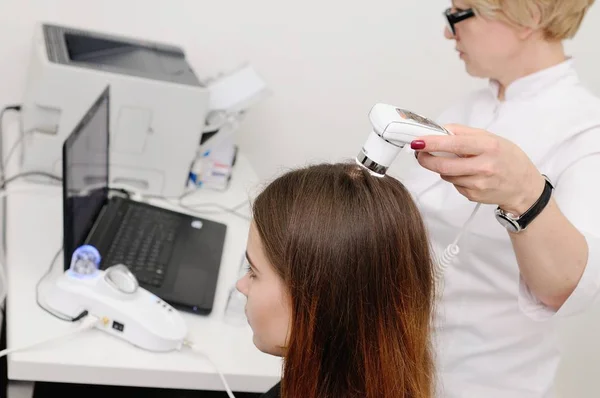 Dermatologis memeriksa seorang wanita pasien rambut menggunakan perangkat khusus — Stok Foto