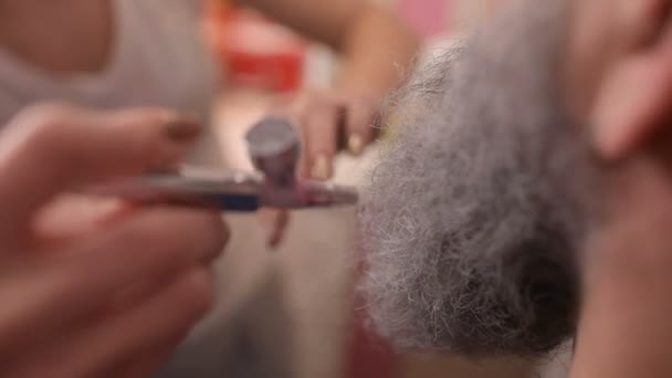 Maquillador hace maquillaje a un hombre con barba gris . — Vídeos de Stock