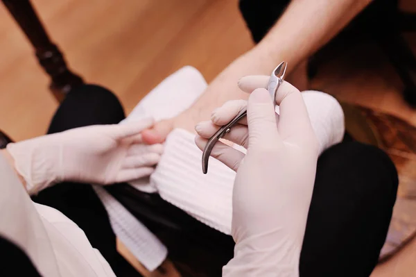 Uma jovem faz um homem pedicure no fundo de um salão de beleza . — Fotografia de Stock