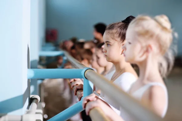 Mladí tanečníci ve studiu baletu. Mladí tanečníci vykonávat gymnastická cvičení na balet nebo barre při zahřívání v učebně. — Stock fotografie