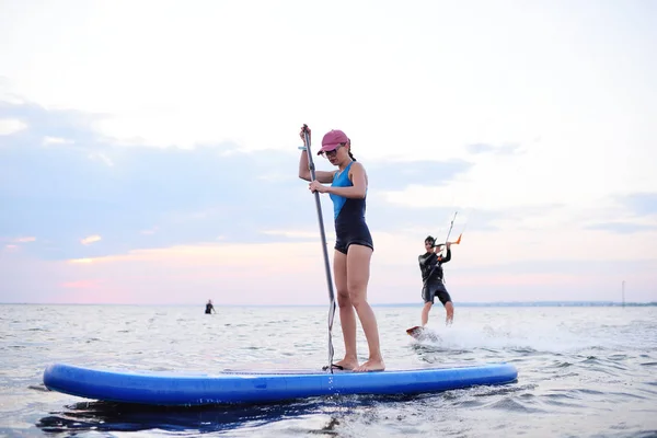 Junges Mädchen mit Sup Board auf dem Hintergrund des Meeres und des Sonnenuntergangs — Stockfoto