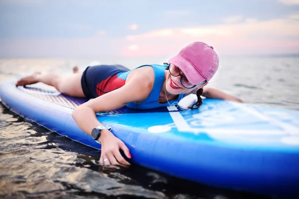 Junges Mädchen mit Sup Board auf dem Hintergrund des Meeres und des Sonnenuntergangs — Stockfoto