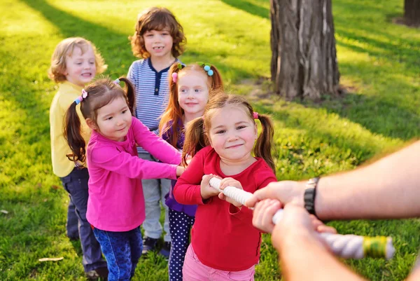 Barnen leka dragkamp i parken. — Stockfoto