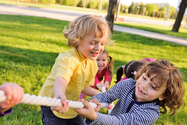 Children play tug of war in the park.