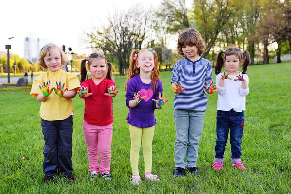 Un grupo de niños pequeños con las manos sucias en el juego de pintura de color en el parque . — Foto de Stock