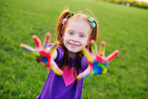 Menina pré-escolar mostra palmas manchadas com pinturas multicoloridas dedo — Fotografia de Stock