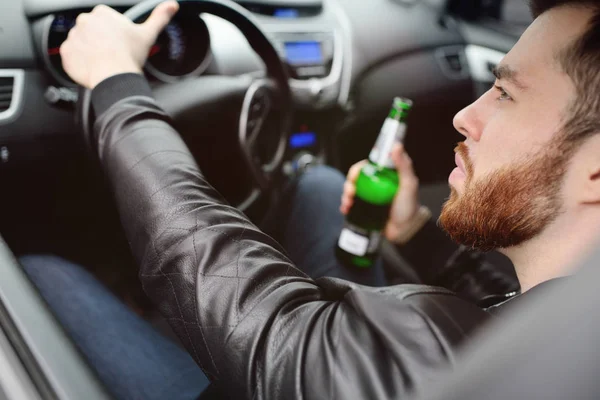 Пьяный мужчина с бутылкой пива за рулём машины — стоковое фото