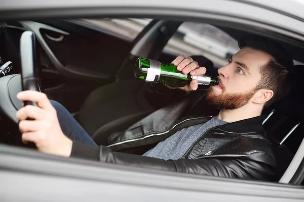 Homem com uma garrafa de cerveja a conduzir um carro — Fotografia de Stock