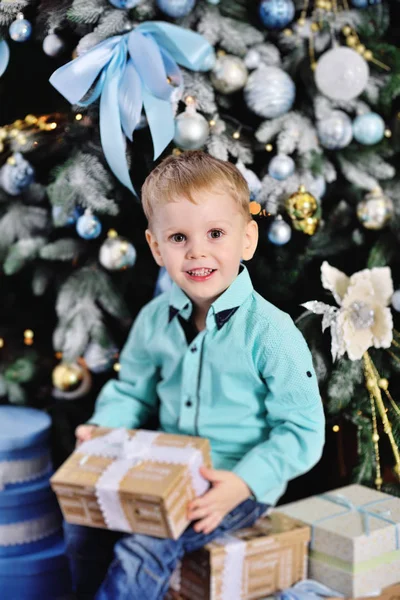 Хлопчик відкриває коробки з подарунками під ялинкою — стокове фото