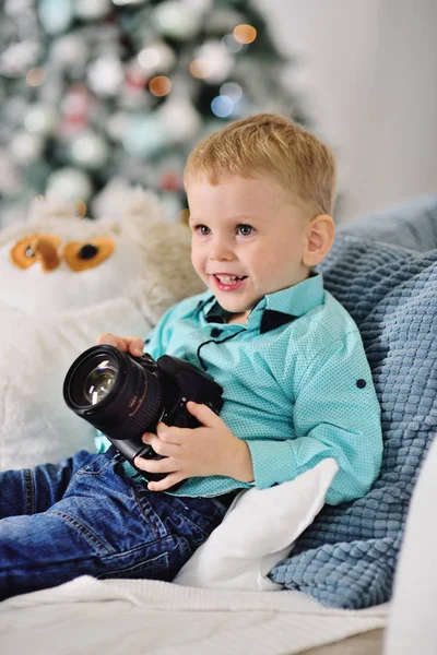 Bebé niño con una cámara SLR en el fondo de una decoración de Navidad —  Fotos de Stock