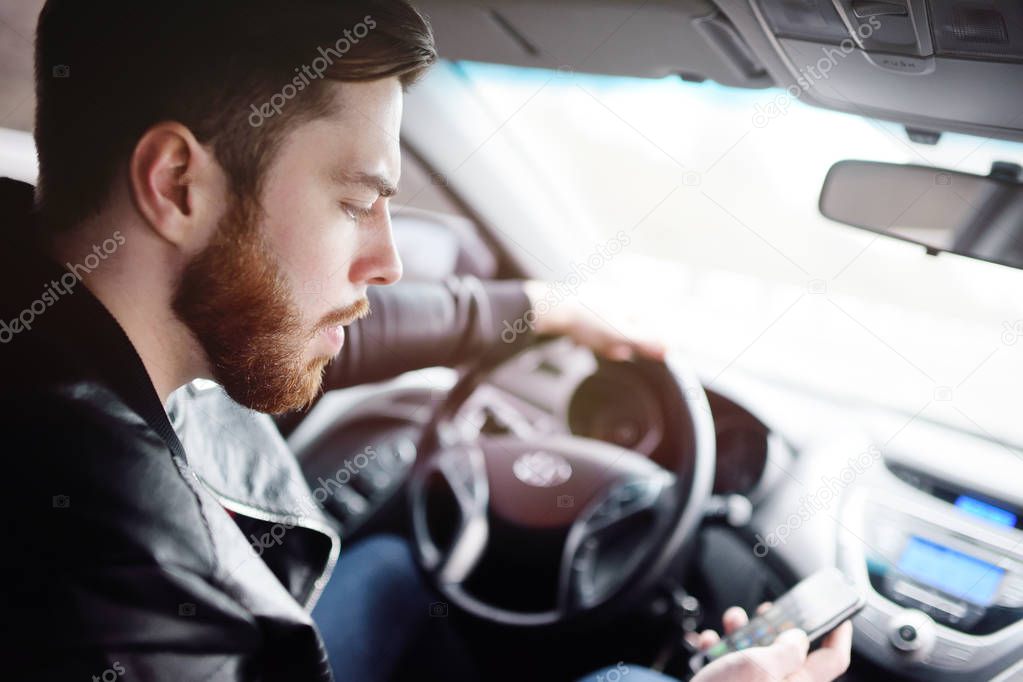 Young man talking on the phone while driving a car