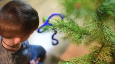 Çocuk Noel ağacını evde oyuncaklarla süslüyor.