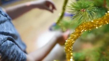 Çocuk Noel ağacını evde oyuncaklarla süslüyor.