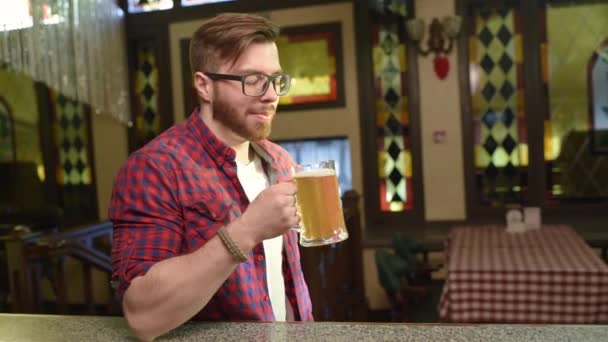 Szakállas jóképű férfi, egy kockás inget, egy pohár sör — Stock videók