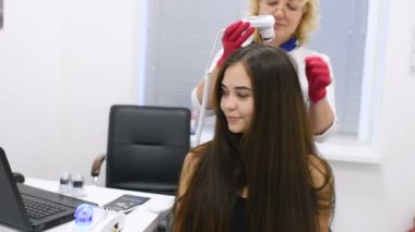 özel bir araç - bir trichoscope ile güzel bir genç kız saç yapısını Doktor dermatolog tanılar.