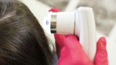 özel bir araç - bir trichoscope ile güzel bir genç kız saç yapısını Doktor dermatolog tanılar.