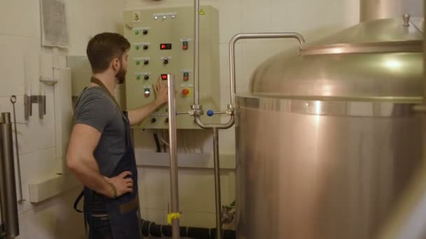 Bryggaren på bakgrunden av öl tankar gör beräkningar — Stockvideo