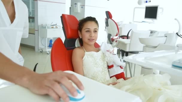 Menina bebê na cadeira dental vermelha em uma recepção dentistas — Vídeo de Stock