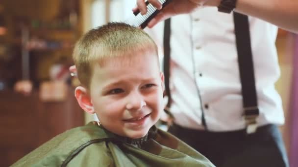 Barbiere fa un taglio di capelli per un piccolo bambino divertente — Video Stock