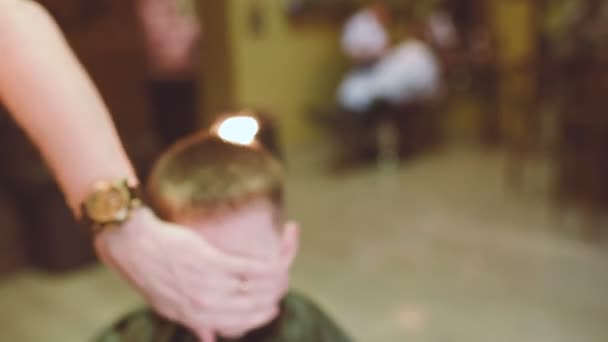 Peluquero hace un corte de pelo para un pequeño niño divertido — Vídeos de Stock