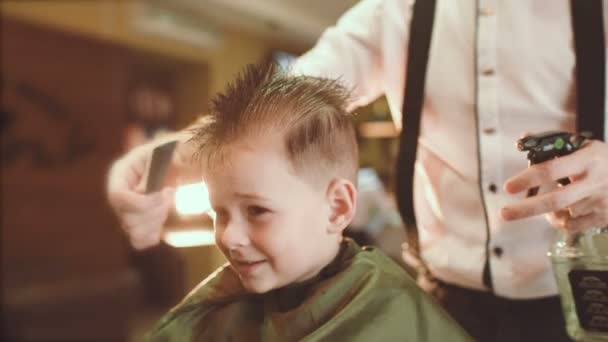 Barbeiro faz um corte de cabelo para um menino engraçado — Vídeo de Stock