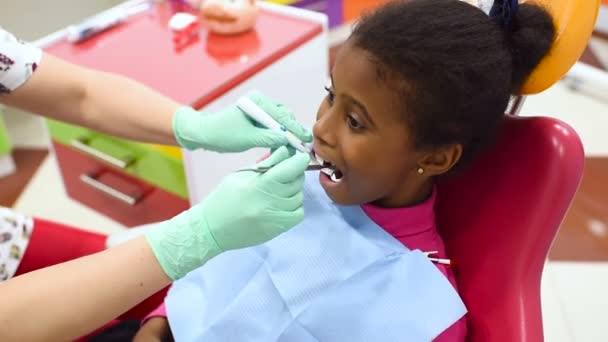 Детский Дантист Осматривает Зубы Маленькой Милой Афроамериканской Девочки Красно Желтом — стоковое видео