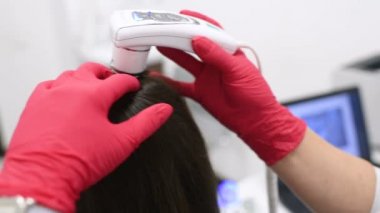 özel bir araç - bir trichoscope ile güzel bir genç kız saç yapısını Doktor dermatolog tanılar.