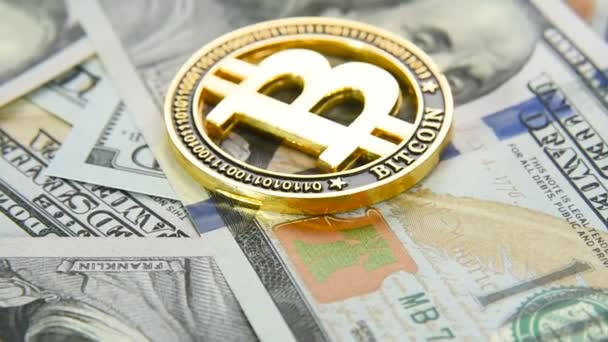 Gouden munten bitcoin sluiten - omhoog op de achtergrond van honderd dollarbiljetten. Cryptocurrency cursus — Stockvideo
