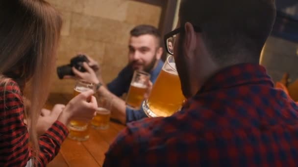 Amigos - chicos y chicas jóvenes bebiendo cerveza, hablando y sonriendo en el bar — Vídeos de Stock