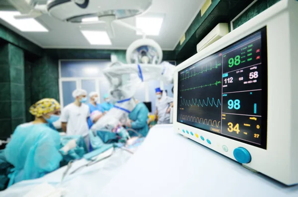 Chirurdzy operują na zbliżenie monitor funkcji życiowych pacjentów. — Zdjęcie stockowe