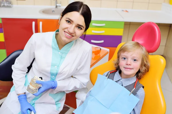 Criança sorridente com cabelo encaracolado leve no exame na cadeira dental — Fotografia de Stock