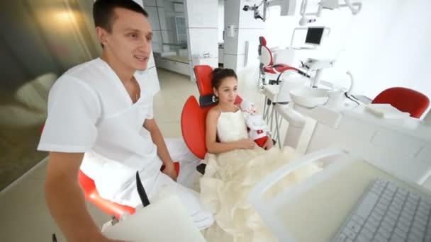 Baby girl in red dental chair at a dentists reception — Stock Video